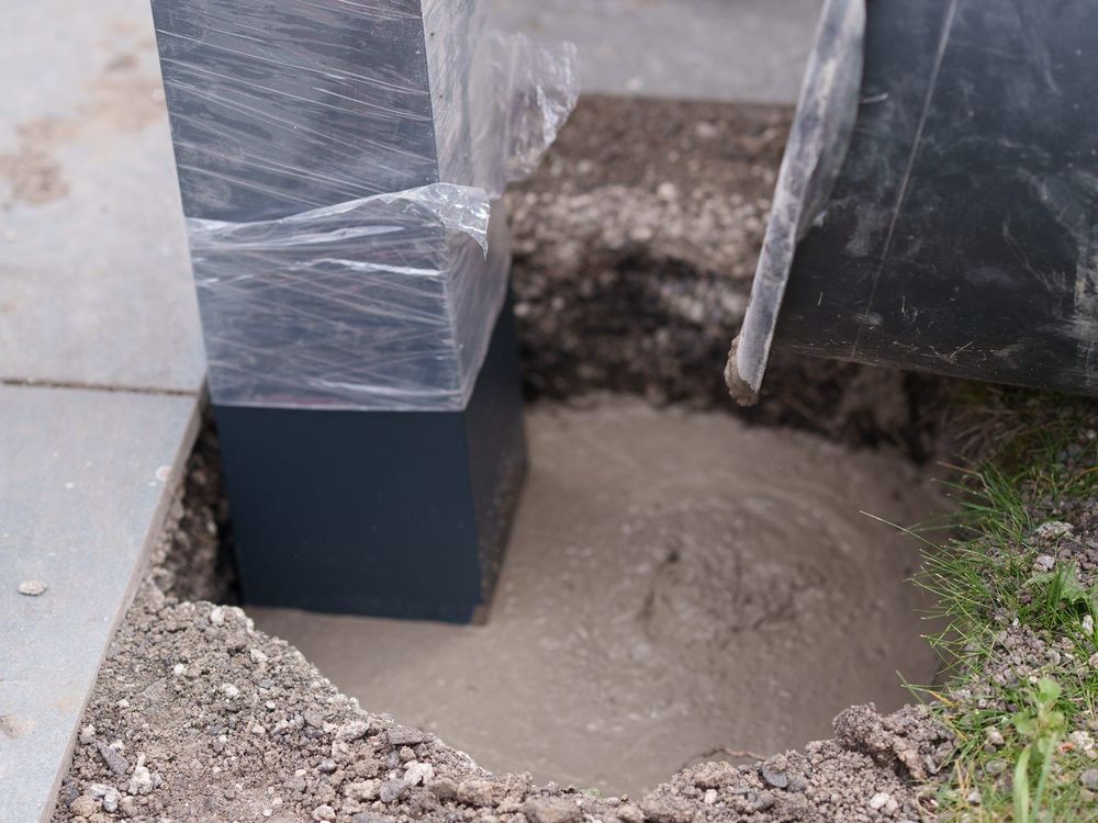Beton wird in das Fundament eines Terrassendach-Pfostens gefüllt
