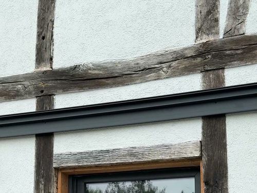 Wandanschlussprofil einer Terrassenüberdachung über einem Fenster an einer Fachwerkfassade