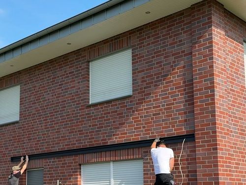 Wandprofil für ein Terrassendach wird an der Klinkerwand ausgerichtet