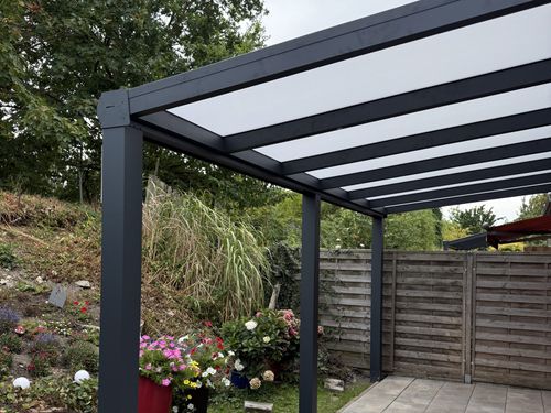 Terrassendach mit opaler Eindeckung über einer gefliesten Terrasse
